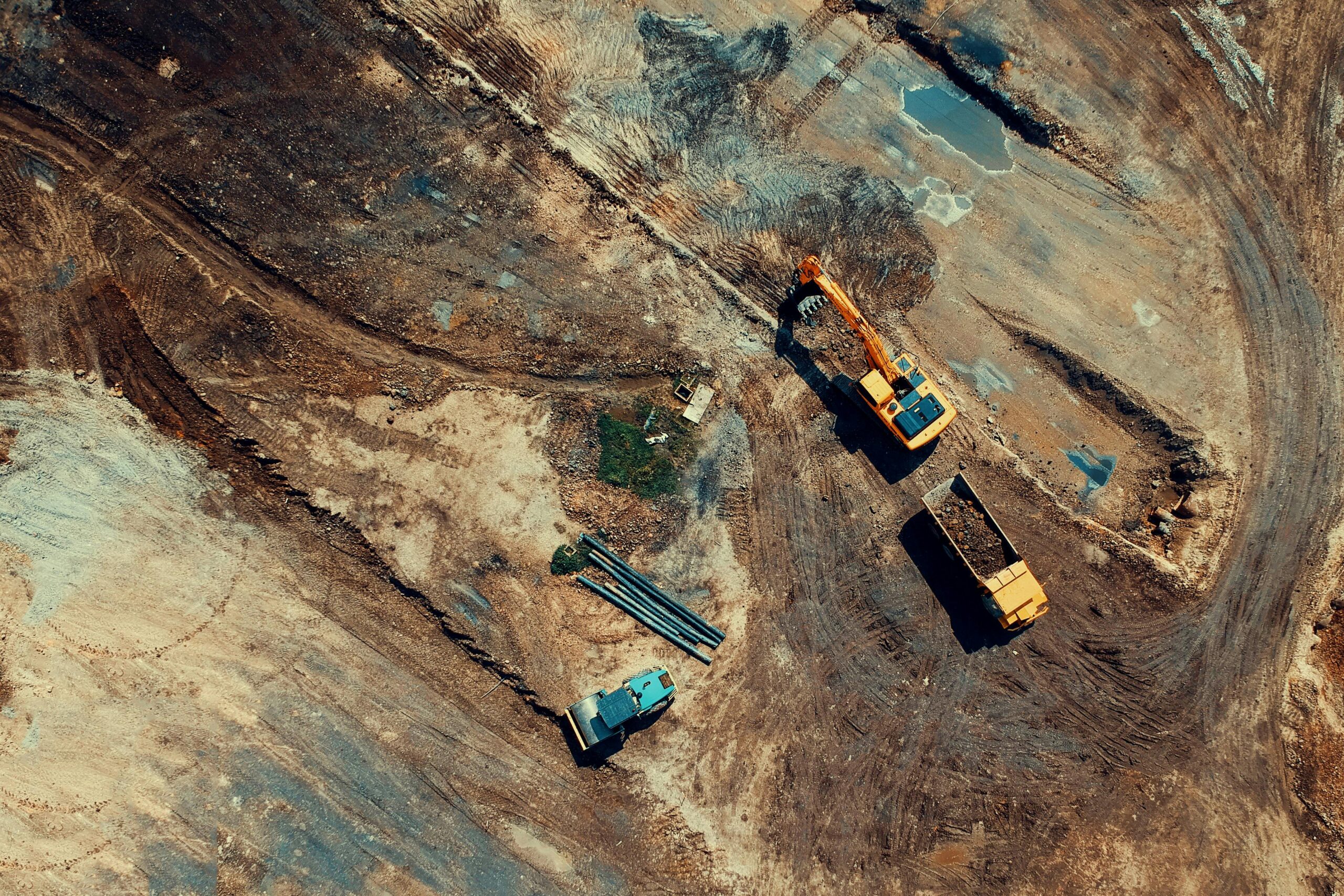 Aerial view of a construction site featuring heavy machinery and trucks, displaying industrial activity.